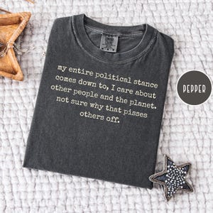 May include: A dark grey t-shirt with the text "my entire political stance comes down to, I care about other people and the planet. not sure why that pisses others off." A round label reads "PEPPER".