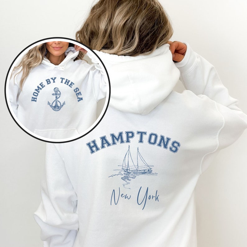 May include: White hooded sweatshirt with a blue anchor and the text "Home by the Sea" on the front and the text "HAMPTONS New York" with a sailboat graphic on the back.