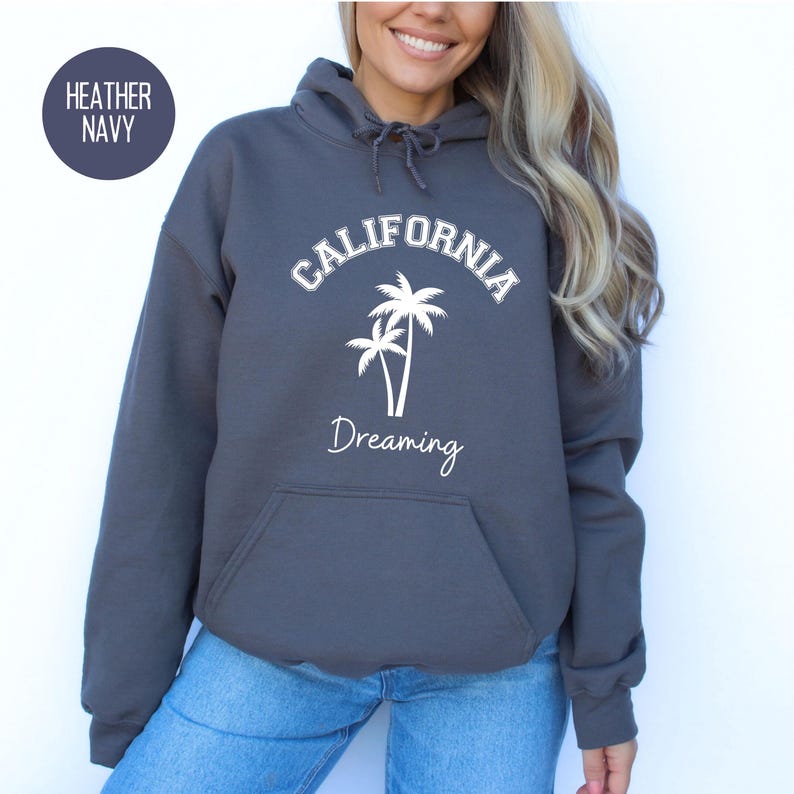 Puede incluir: Sudadera con capucha de color azul marino jaspeado con el texto "CALIFORNIA DREAMING" en letras blancas y un gr&aacute;fico de dos palmeras.