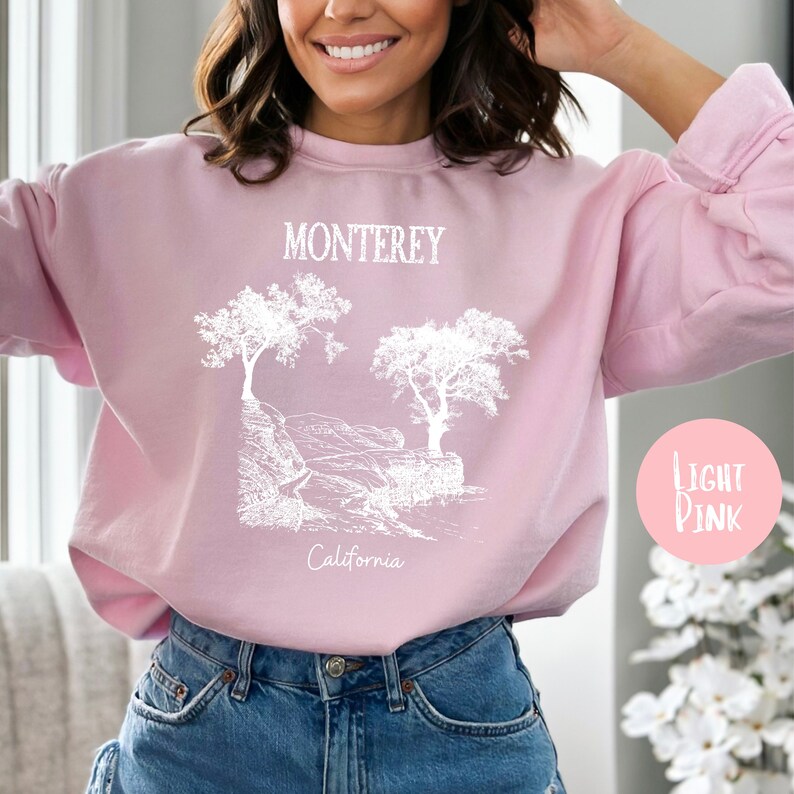 May include: A light pink sweatshirt with a white graphic design of trees and the text "Monterey, California".