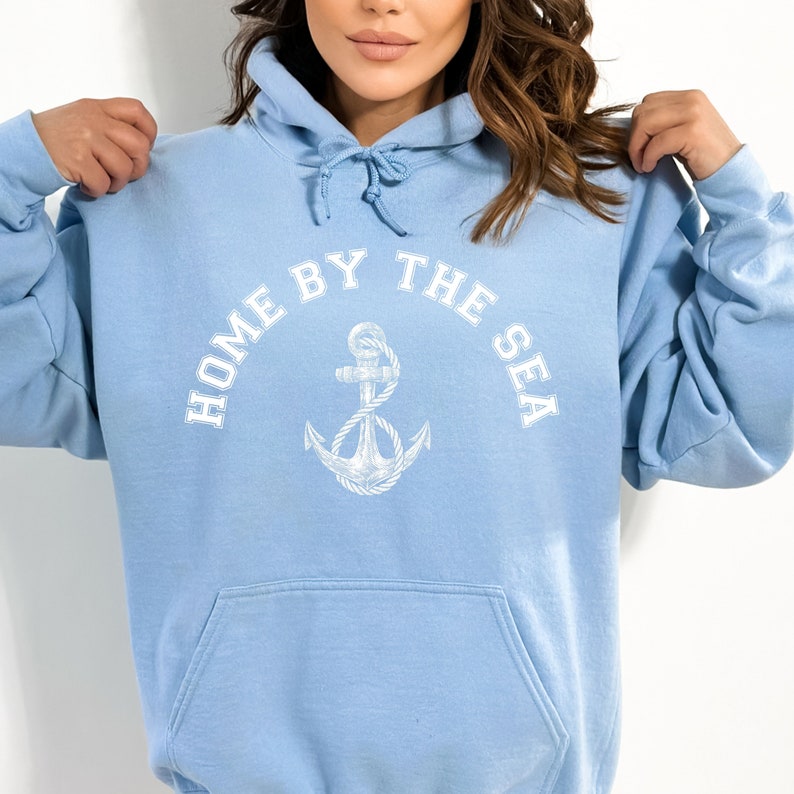 May include: A light blue hoodie with a white anchor and the text "Home by the Sea" printed on the front.