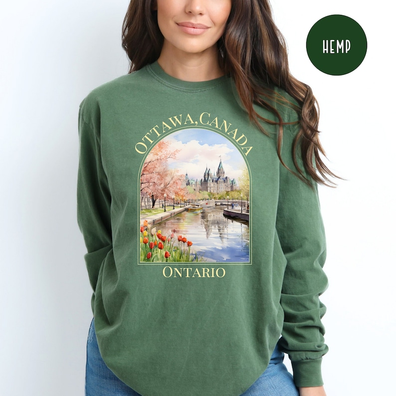 May include: Green long-sleeve hemp sweatshirt with a graphic print of the Parliament Buildings in Ottawa, Canada. The print includes the text "OTTAWA, CANADA" and "ONTARIO".