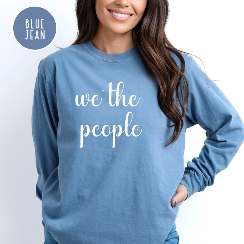 Puede incluir: Una sudadera de manga larga azul jean con el texto "We the People" impreso en blanco en la parte delantera.