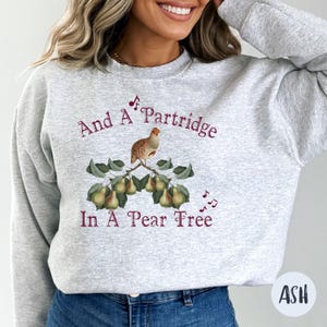 May include: A gray sweatshirt with a maroon print of a partridge in a pear tree. The text reads "And A Partridge In A Pear Tree".