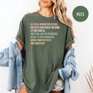 May include: Olive green t-shirt with the text "ALL OF US, REGARDLESS OF RACE, ARE 99.9% GENETICALLY THE SAME. LET THAT SINK IN. WHY THEN, ARE WE SO FOCUSED ON THE .1% THAT DIVIDES US, RATHER THAN THE 99.9% THAT UNITES US?"