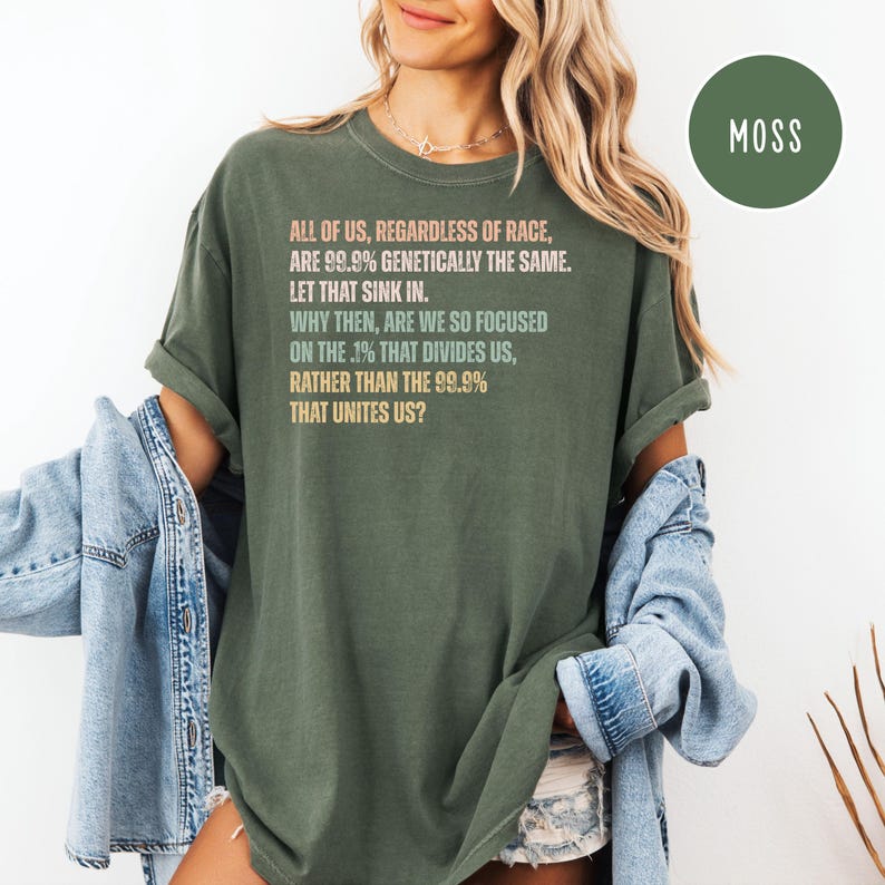 May include: Olive green t-shirt with the text "ALL OF US, REGARDLESS OF RACE, ARE 99.9% GENETICALLY THE SAME. LET THAT SINK IN. WHY THEN, ARE WE SO FOCUSED ON THE .1% THAT DIVIDES US, RATHER THAN THE 99.9% THAT UNITES US?"