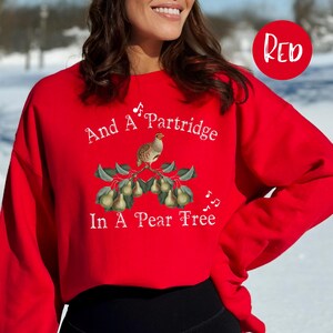 May include: Red sweatshirt with a white graphic of a partridge in a pear tree and the text "And A Partridge In A Pear Tree".