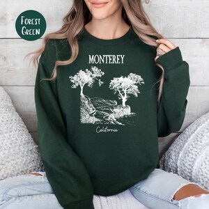 May include: Forest green sweatshirt with a white graphic of trees and the text "Monterey, California".