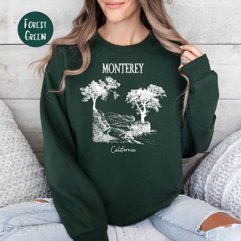 May include: Forest green sweatshirt with a white graphic of trees and the text "Monterey, California".