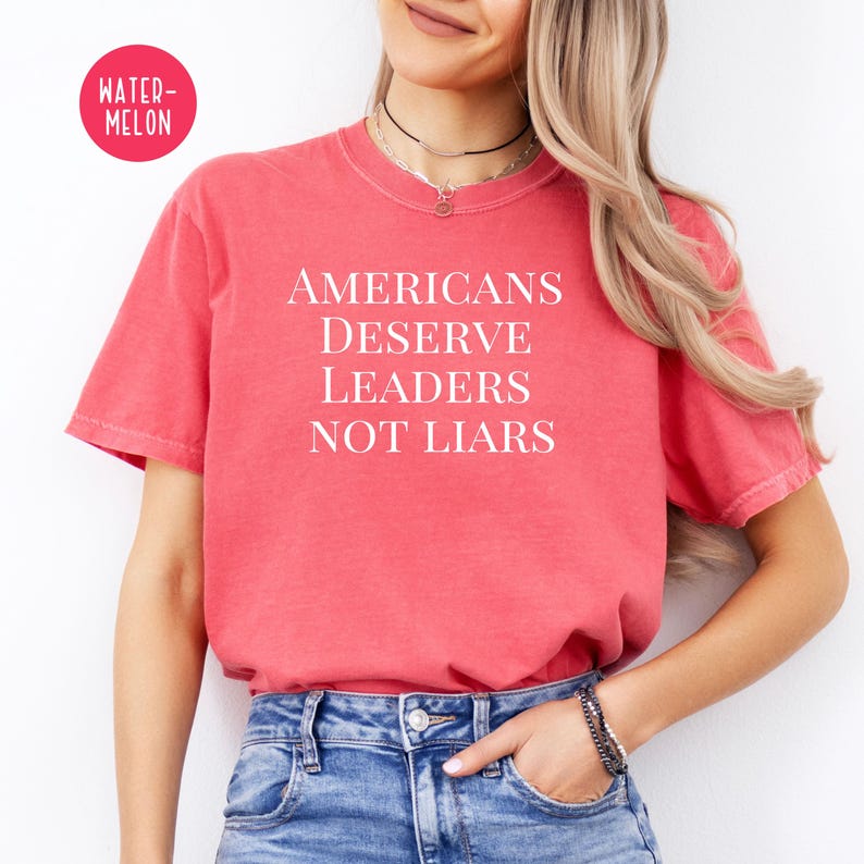 May include: A red t-shirt with the text "Americans Deserve Leaders Not Liars" printed in white.