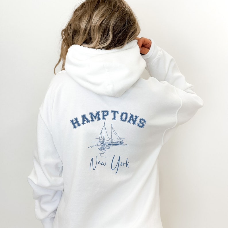 May include: White hooded sweatshirt with a blue graphic of a sailboat and the text "HAMPTONS New York" on the back.