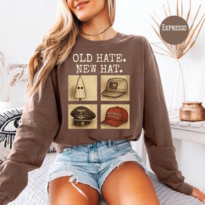 May include: Brown sweatshirt with the text "OLD HATE. NEW HAT." and four images of hats. The images include a white pointed hood, a tan cap, a black military hat, and a red baseball cap with the text "MAKE AMERICA GREAT AGAIN."