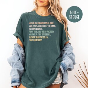 May include: Dark teal t-shirt with the text "ALL OF US, REGARDLESS OF RACE, ARE 99.9% GENETICALLY THE SAME. LET THAT SINK IN. WHY THEN, ARE WE SO FOCUSED ON THE .1% THAT DIVIDES US, RATHER THAN THE 99.9% THAT UNITES US?" in a light orange font.