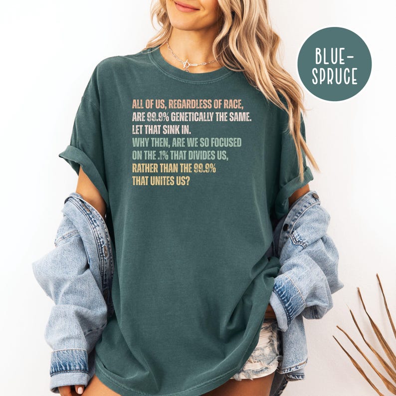May include: Dark teal t-shirt with the text "ALL OF US, REGARDLESS OF RACE, ARE 99.9% GENETICALLY THE SAME. LET THAT SINK IN. WHY THEN, ARE WE SO FOCUSED ON THE .1% THAT DIVIDES US, RATHER THAN THE 99.9% THAT UNITES US?" in a light orange font.