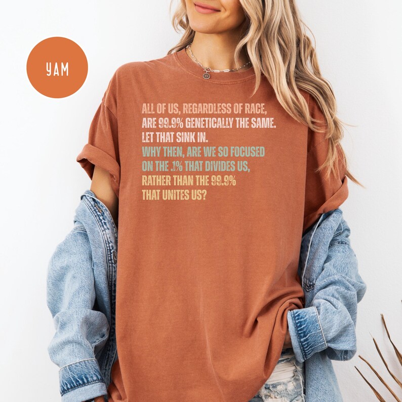 May include: Rust-colored t-shirt with the text "ALL OF US, REGARDLESS OF RACE, ARE 99.9% GENETICALLY THE SAME. LET THAT SINK IN. WHY THEN, ARE WE SO FOCUSED ON THE .1% THAT DIVIDES US, RATHER THAN THE 99.9% THAT UNITES US?" and a YAM logo.