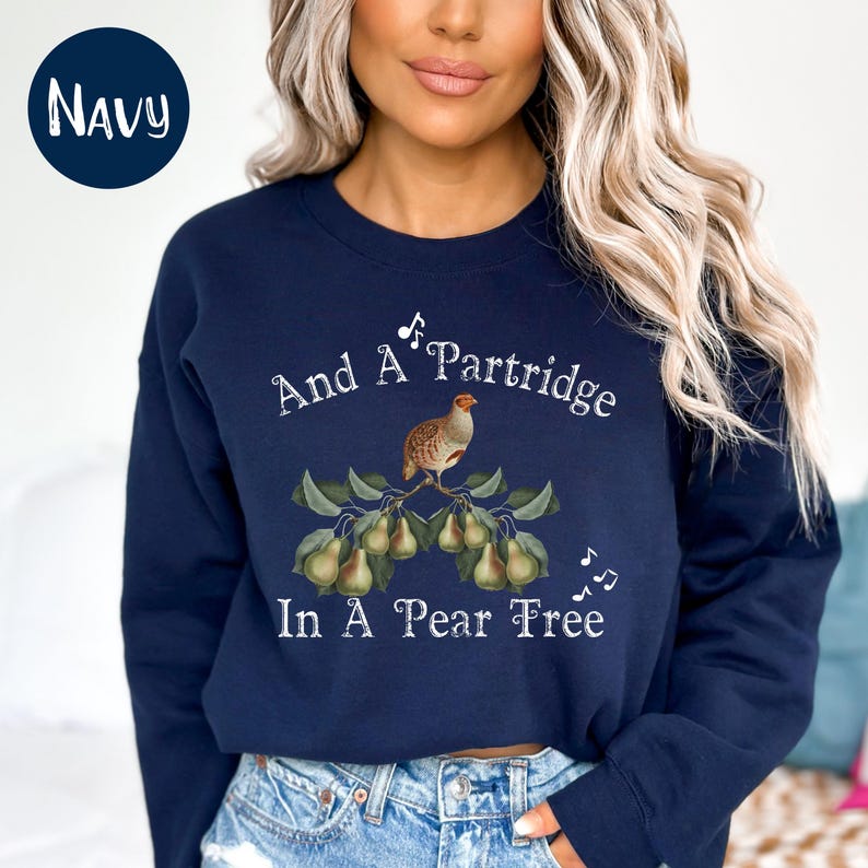 May include: A navy blue sweatshirt with a white graphic of a partridge in a pear tree. The graphic includes the text "And A Partridge In A Pear Tree" and musical notes.