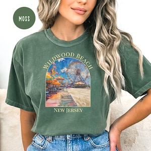 May include: A green t-shirt with a vintage-style illustration of the Wildwood Beach Ferris wheel and boardwalk. The text "Wildwood Beach New Jersey" is printed on the shirt.
