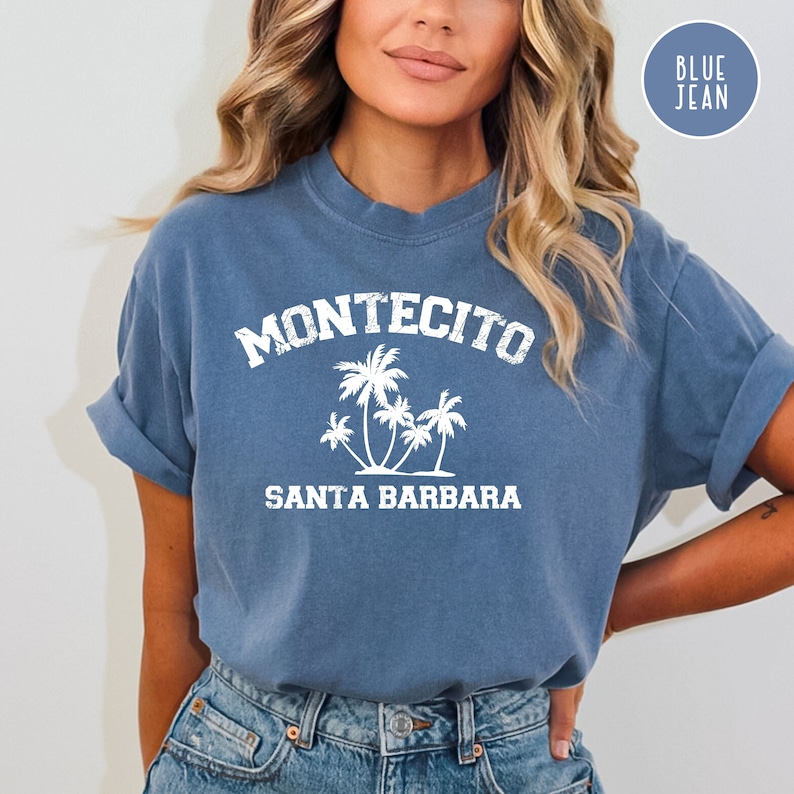 May include: A blue jean t-shirt with white text that reads "Montecito Santa Barbara" and a graphic of palm trees.