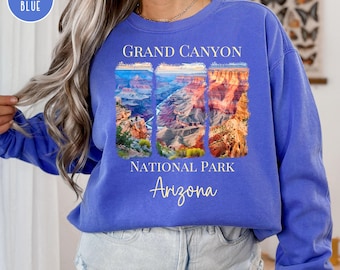 May include: A blue sweatshirt with a graphic of the Grand Canyon National Park in Arizona. The graphic features three photos of the canyon with the text "Grand Canyon National Park Arizona" below.
