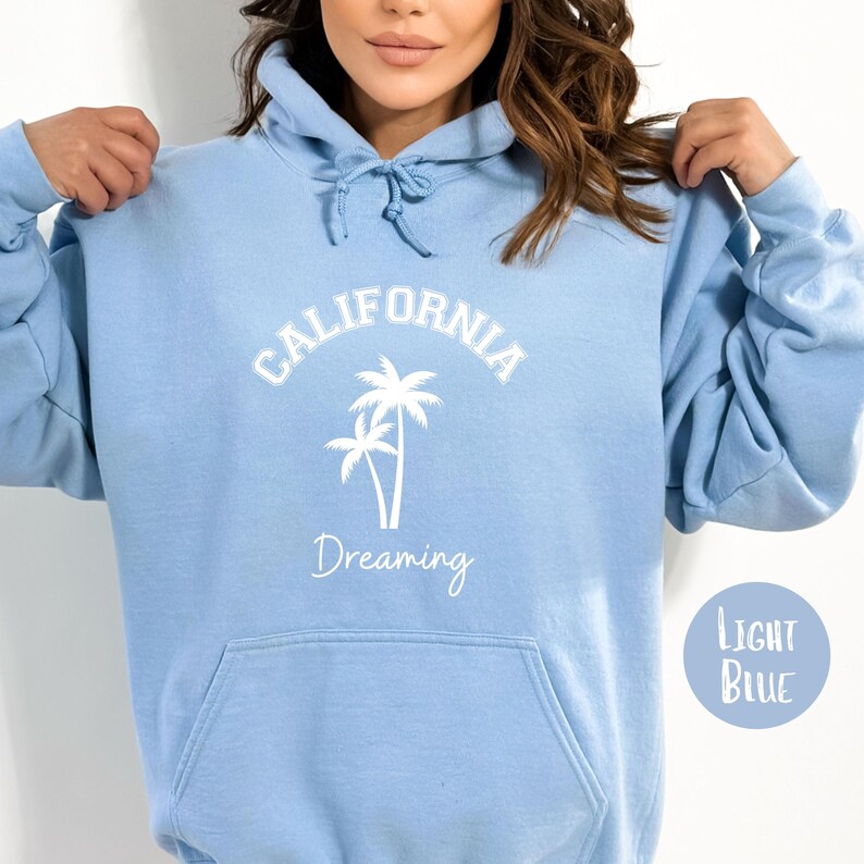 Puede incluir: Sudadera con capucha azul claro con un gr&aacute;fico blanco de palmeras y el texto "CALIFORNIA Dreaming".