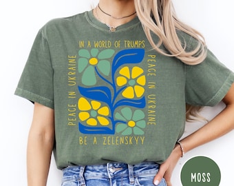 May include: A green t-shirt with a floral design and the text "Peace in Ukraine in a world of Trumps, Be a Zelenskyy".