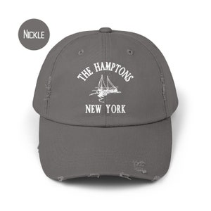 May include: A gray distressed baseball cap with white embroidered text that reads "The Hamptons New York" and a sailboat graphic.