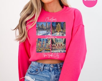 May include: A pink cropped sweatshirt with a graphic design featuring four images of New York City during Christmas time. The text "Christmas Vacation in New York City" is printed on the sweatshirt.