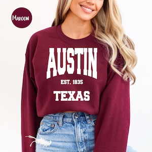 May include: A maroon sweatshirt with white text that reads "Austin Est. 1835 Texas".