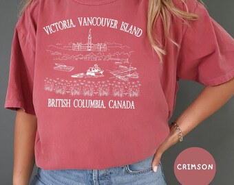 May include: Crimson red t-shirt with a white graphic design featuring the text "Victoria, Vancouver Island, British Columbia, Canada" and a drawing of the Parliament Buildings and boats.