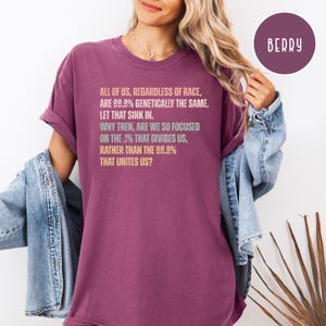 May include: A berry-colored t-shirt with the text "ALL OF US, REGARDLESS OF RACE, ARE 99.9% GENETICALLY THE SAME. LET THAT SINK IN. WHY THEN, ARE WE SO FOCUSED ON THE .1% THAT DIVIDES US, RATHER THAN THE 99.9% THAT UNITES US?"