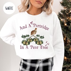 May include: White sweatshirt with a Christmas-themed design. The design features a partridge on a pear tree with the text "And A Partridge In A Pear Tree".