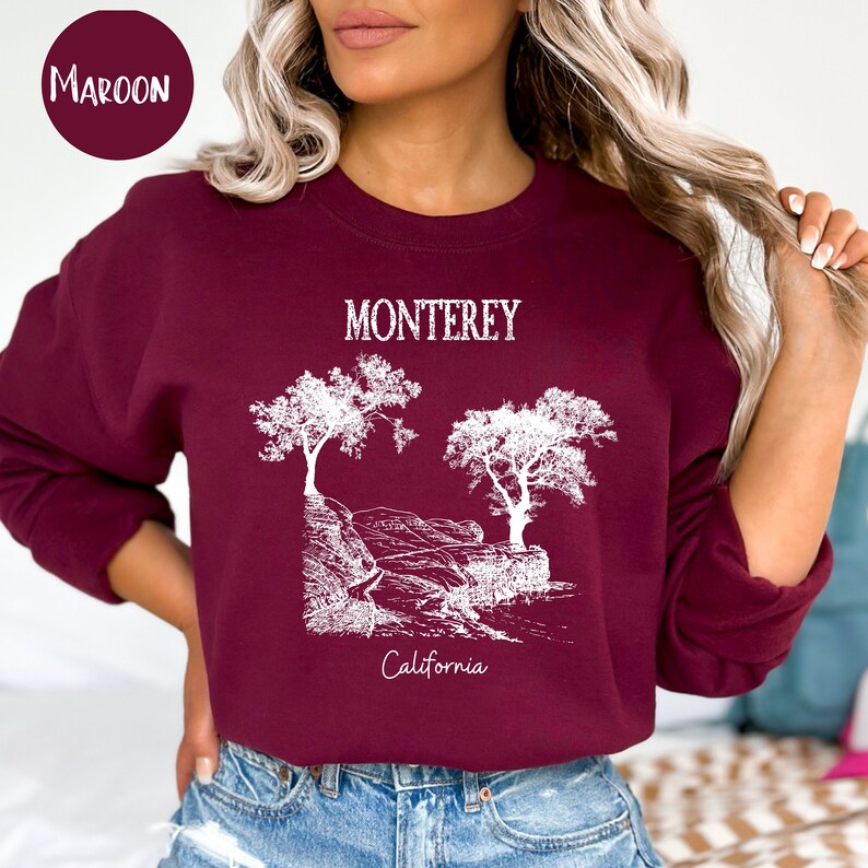 May include: A maroon sweatshirt with a white graphic design of trees and the text "Monterey California".