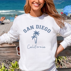 May include: White sweatshirt with a blue graphic print of palm trees and the text "San Diego California".
