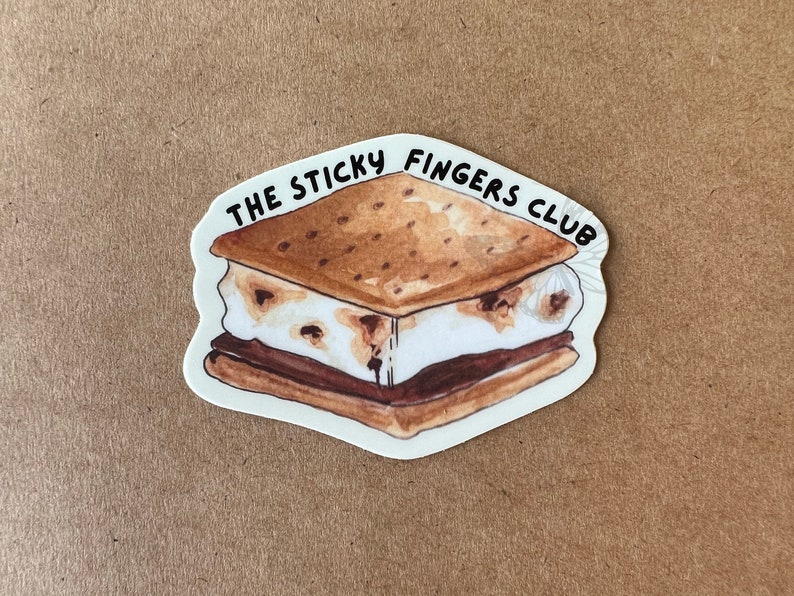 K&ouml;nnte beinhalten: Ein wei&szlig;er Aufkleber mit einer Cartoon-Illustration eines S'mores. Der Text "THE STICKY FINGERS CLUB" ist um den S'more herum geschrieben.