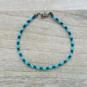 Könnte beinhalten: Ein blaues und grünes Perlenarmband mit einem silbernen Verschluss.