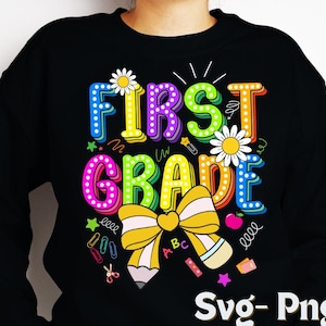 Könnte beinhalten: Schwarzes Sweatshirt mit einem farbenfrohen "FIRST GRADE"-Aufdruck. Das Design umfasst Gänseblümchen, eine gelbe Schleife, einen Bleistift und Schulmaterial. Der Text ist in einer verspielten, mehrfarbigen Schriftart gehalten.