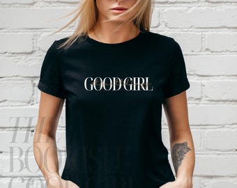 May include: A black t-shirt with the text "GOOD GIRL" printed in white on the front.