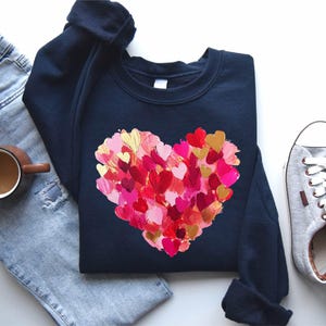 a t - shirt with a heart painted on it next to a pair of jeans