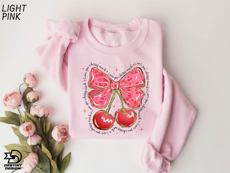 a pink sweater with a bow and cherries on it