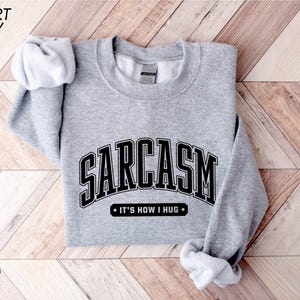 a gray sweatshirt with a black and white logo on it