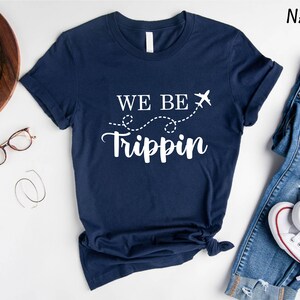 a t - shirt that says we be trippin next to a pair of jeans