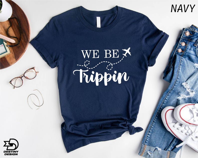 a t - shirt that says we be trippin next to a pair of jeans