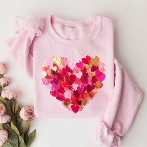 a pink sweater with hearts painted on it