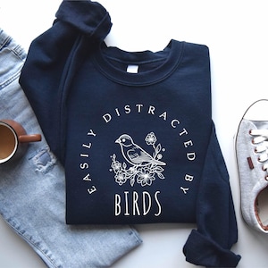 a t - shirt with a bird on it next to a pair of jeans
