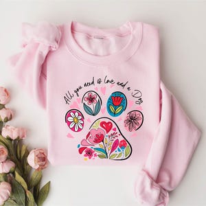 a pink sweater with a paw print on it