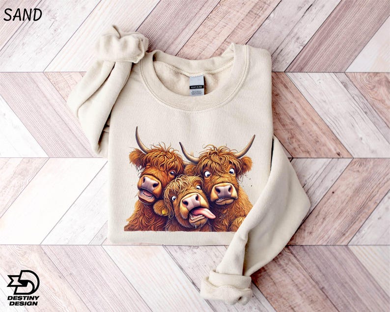 A beige sweater with a printed image of three yaks with horns and wide-open mouths, appearing to be making a funny or playful expression.