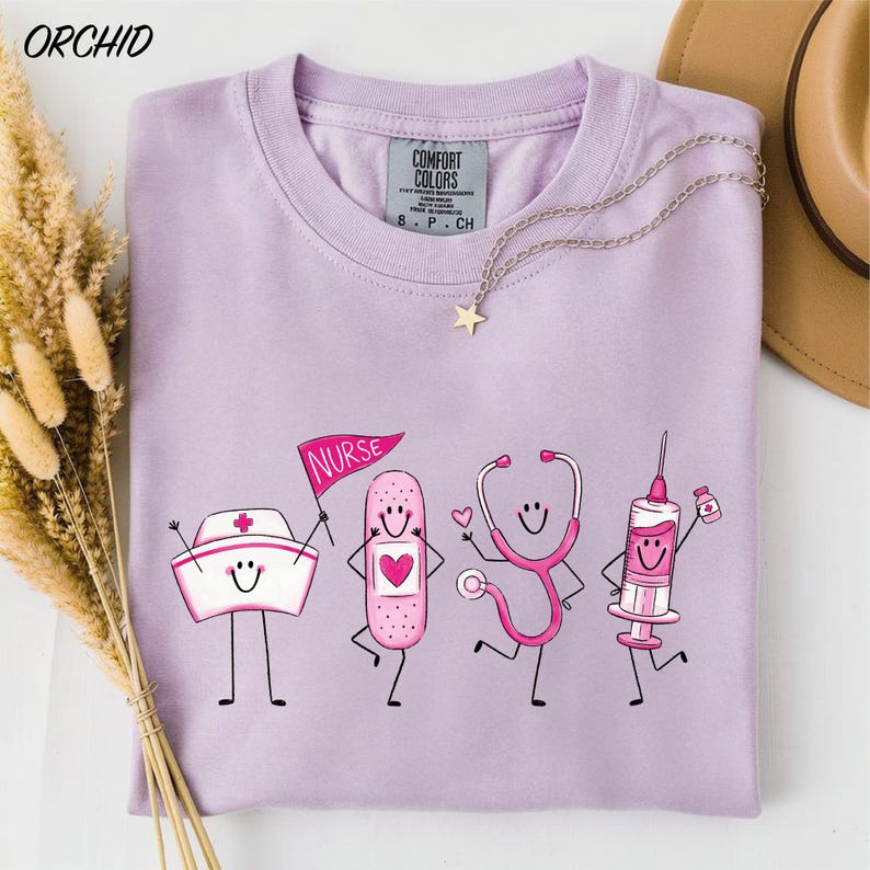 A purple t-shirt with a graphic design depicting four cartoon nurse characters, including a nurse holding a stethoscope, a nurse holding a heart, a nurse holding a syringe, and a nurse holding a bandage.