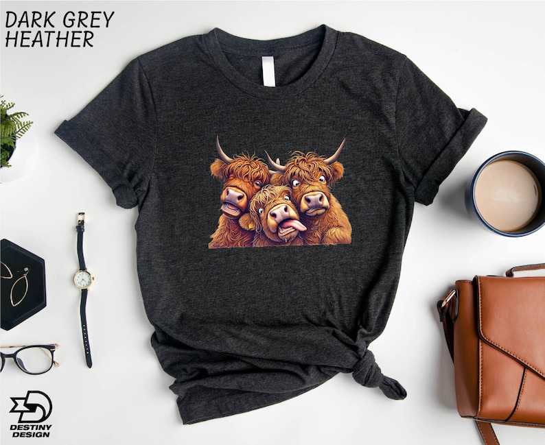 a black t-shirt with a graphic of three yaks or long-haired cows, along with a watch, a cup of coffee, and a handbag.