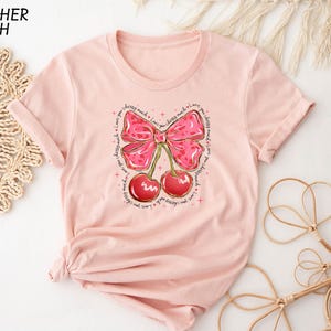 a pink shirt with a pink bow and cherries on it