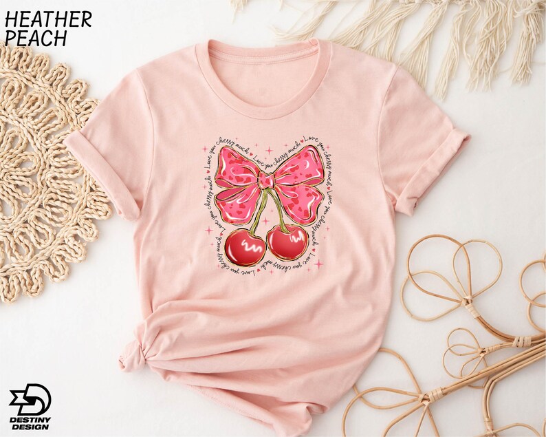 a pink shirt with a pink bow and cherries on it